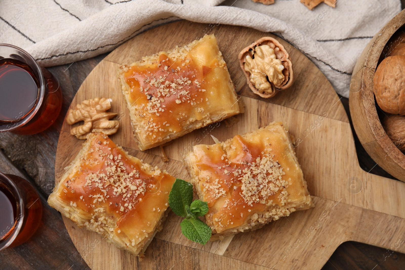 Photo of Eastern sweets. Pieces of tasty baklava and tea on wooden table, flat lay