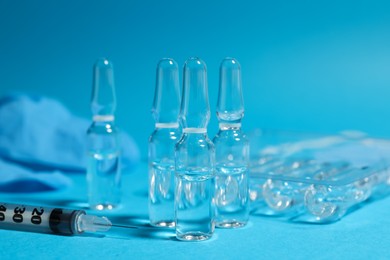 Photo of Pharmaceutical ampoules and syringe on light blue background