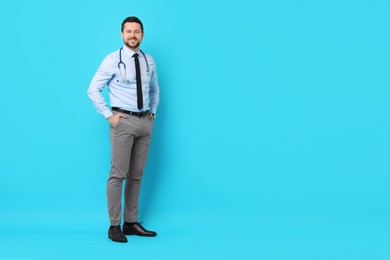 Smiling doctor with stethoscope on light blue background. Space for text