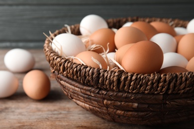 Photo of Basket with raw chicken eggs on wooden table