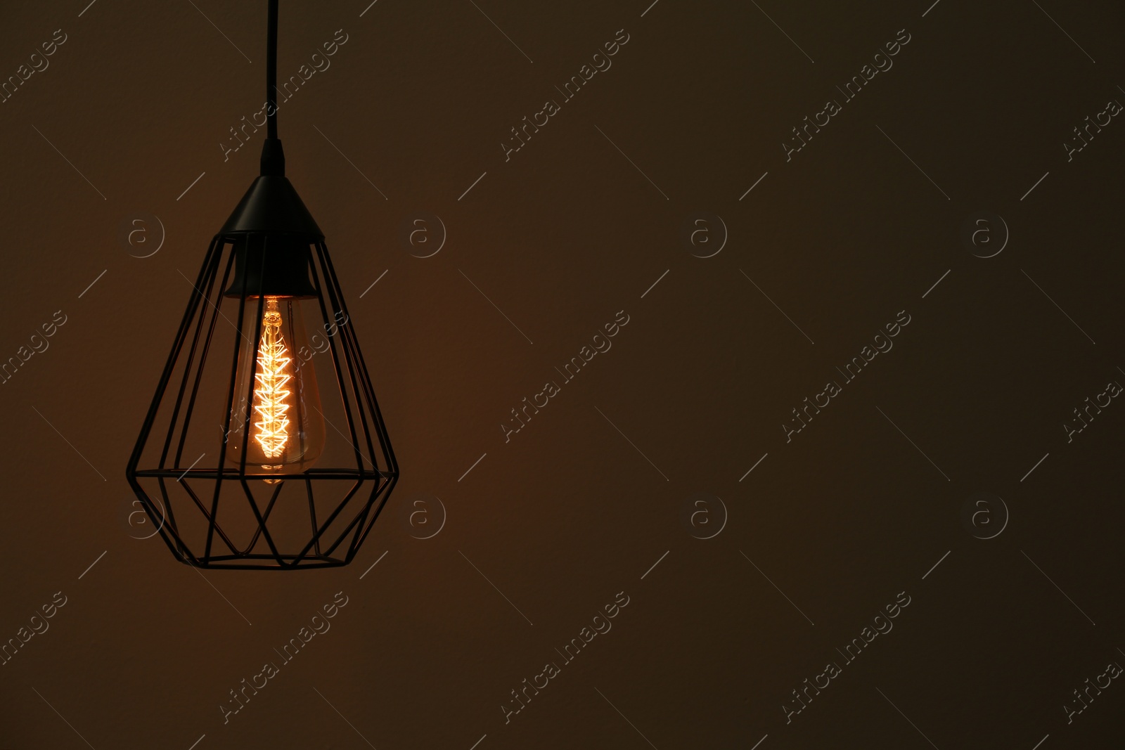 Photo of Hanging lamp bulb in chandelier against dark background, space for text