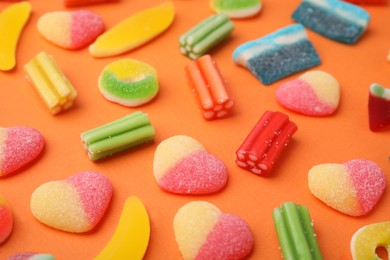 Many different jelly candies on orange background