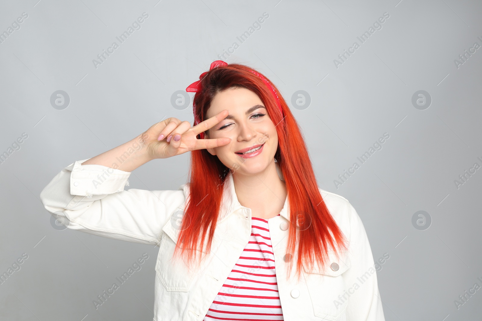 Photo of Young woman with bright dyed hair on grey background