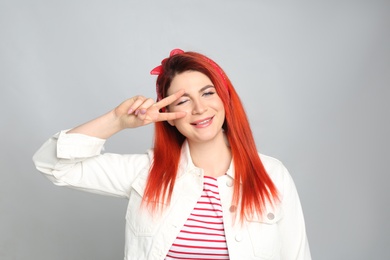 Photo of Young woman with bright dyed hair on grey background