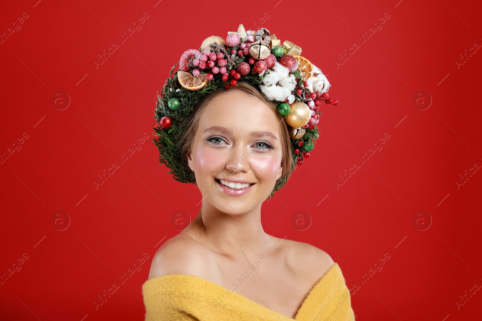 Photo of Beautiful young woman wearing Christmas wreath on red background