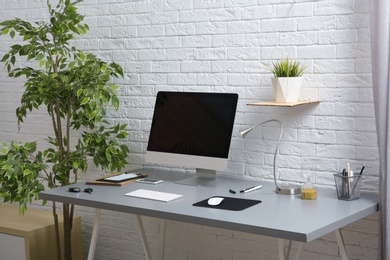 Photo of Interior of comfortable work place with computer on table at home