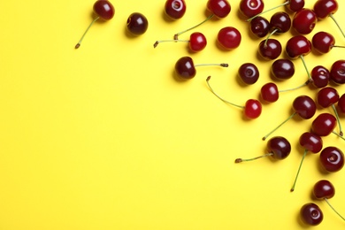 Photo of Sweet juicy cherries on yellow background, flat lay. Space for text
