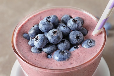 Photo of Glass with blueberry smoothie on grey background, closeup