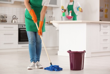 Photo of Woman cleaning floor with mop in kitchen, closeup