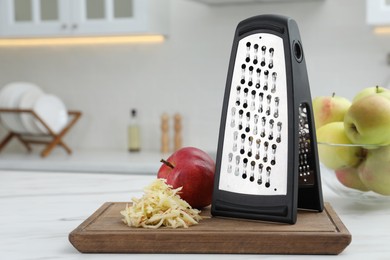 Grater and fresh ripe apples on white table in kitchen. Space for text