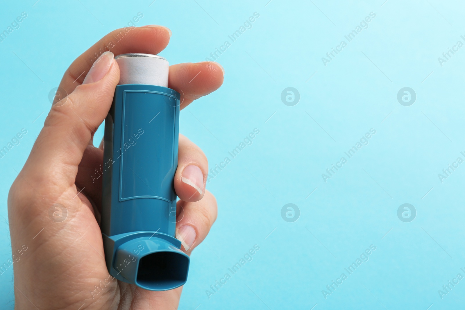 Photo of Woman holding asthma inhaler on color background. Space for text