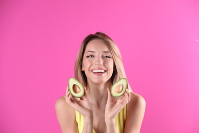 Portrait of young beautiful woman with ripe delicious avocado on color background