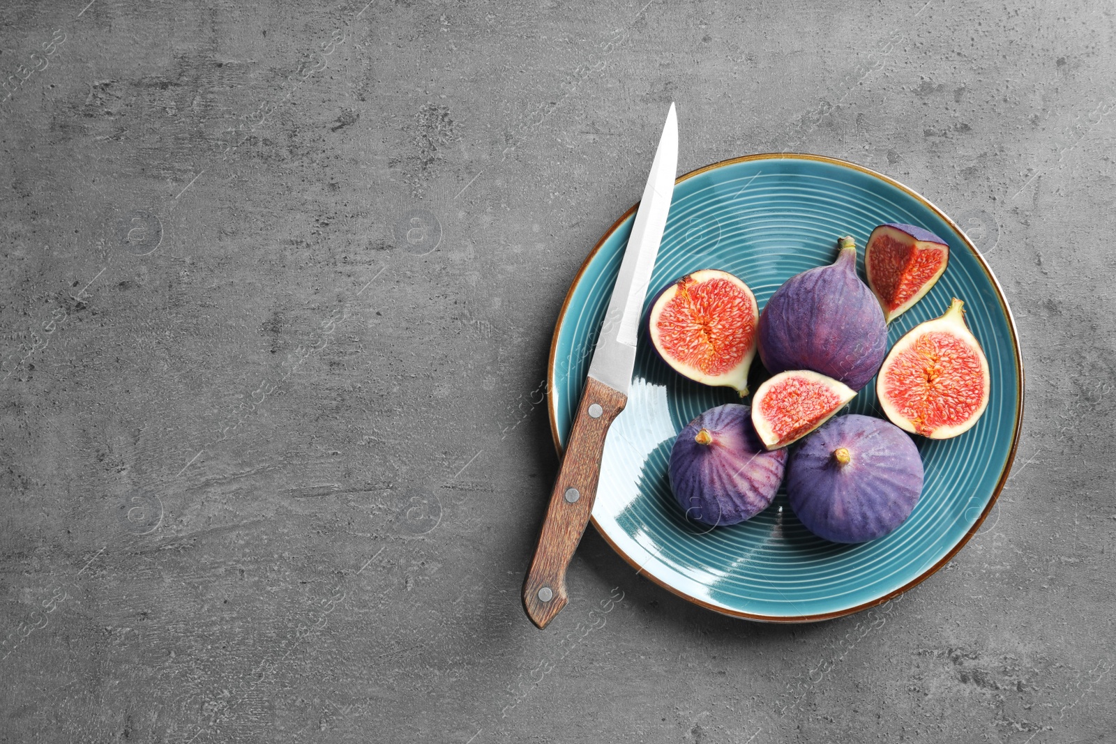 Photo of Plate with fresh ripe figs and knife on gray background, top view. Space for text