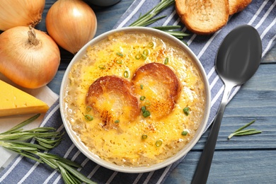 Photo of Tasty homemade french onion soup served on blue wooden table, flat lay