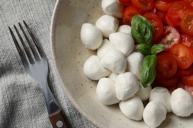 Delicious mozzarella balls, tomatoes and fork on table, flat lay