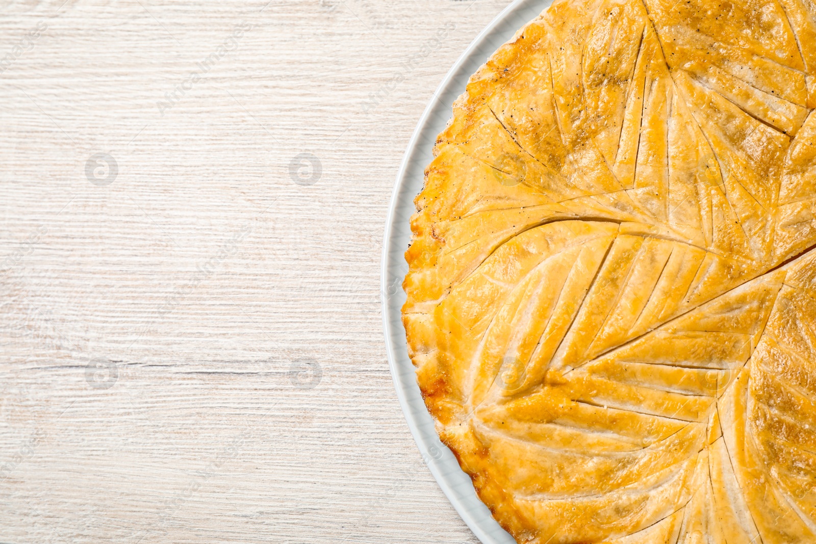 Photo of Traditional galette des rois on white wooden table, top view. Space for text