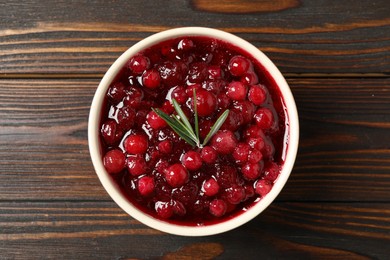 Photo of Fresh cranberry sauce with rosemary on wooden table, top view