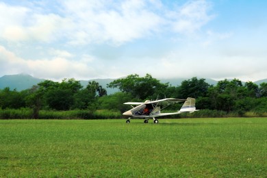 Photo of Light aircraft on grass near trees and mountains