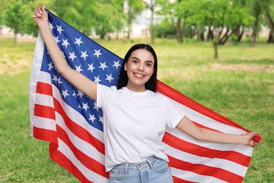 4th of July - Independence day of America. Happy woman with national flag of United States in park