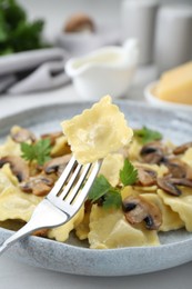 Photo of Delicious ravioli with mushrooms and fork on white table, closeup