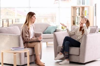 Photo of Young female psychologist working with teenage girl in office