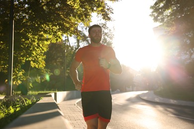 Photo of Athletic man running outdoors on sunny day