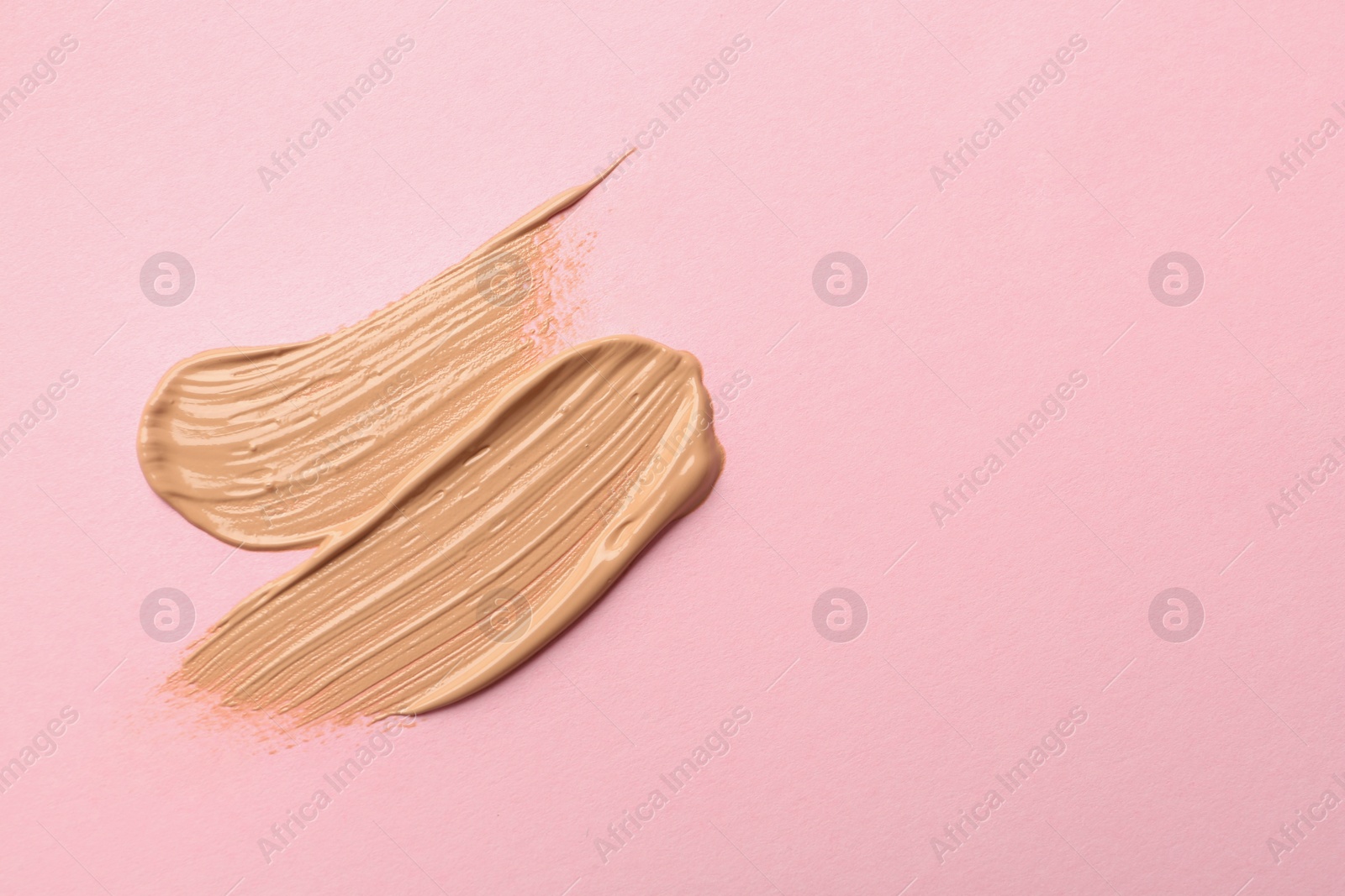 Photo of Sample of liquid skin foundation on pink background, top view. Space for text