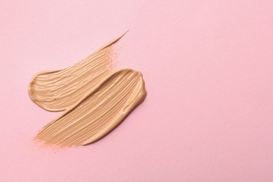 Sample of liquid skin foundation on pink background, top view. Space for text