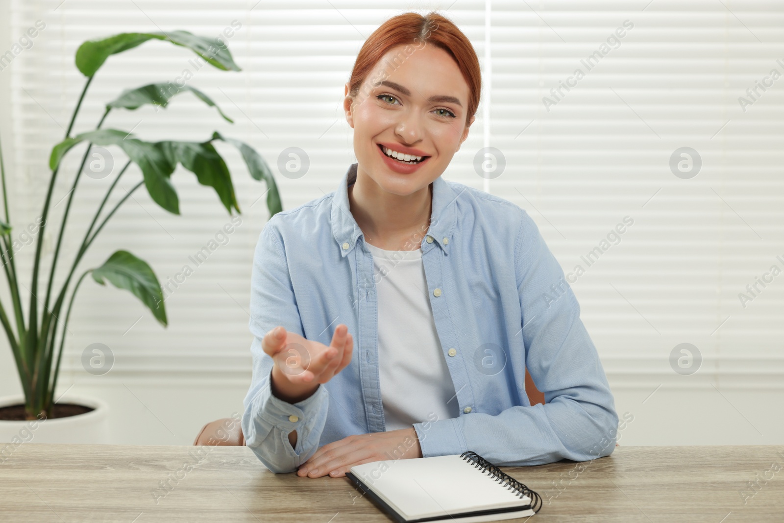 Photo of Young woman having video chat at wooden table indoors, view from web camera