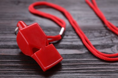 One red whistle with cord on wooden table, closeup