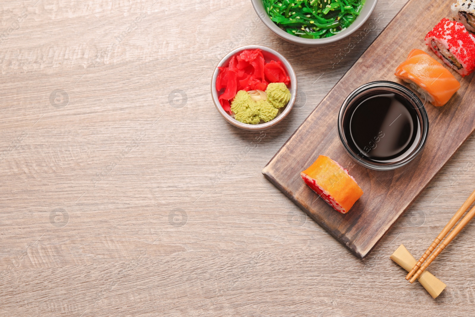 Photo of Flat lay composition with delicious sushi rolls on wooden table. Space for text