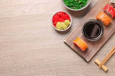 Photo of Flat lay composition with delicious sushi rolls on wooden table. Space for text