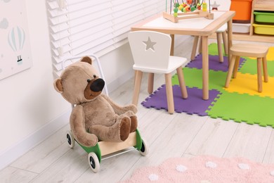 Photo of Stylish kindergarten interior with cute teddy bear on floor and other toys