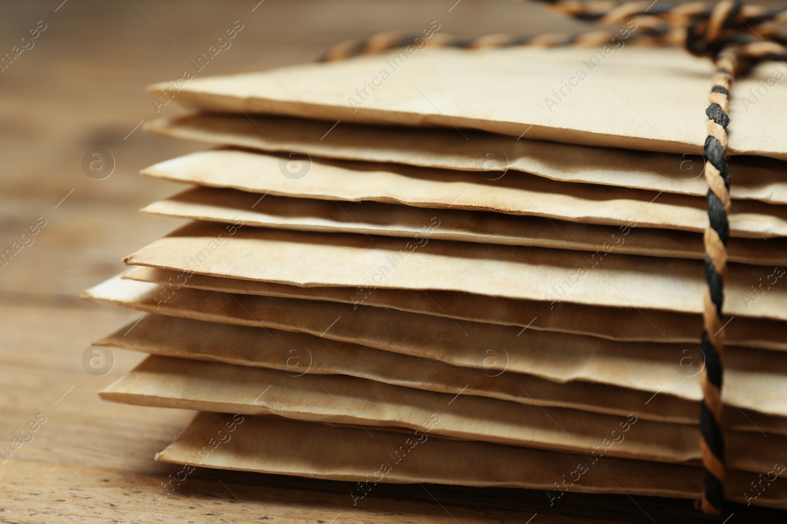 Photo of Stack of old letters tied with string on wooden table, closeup