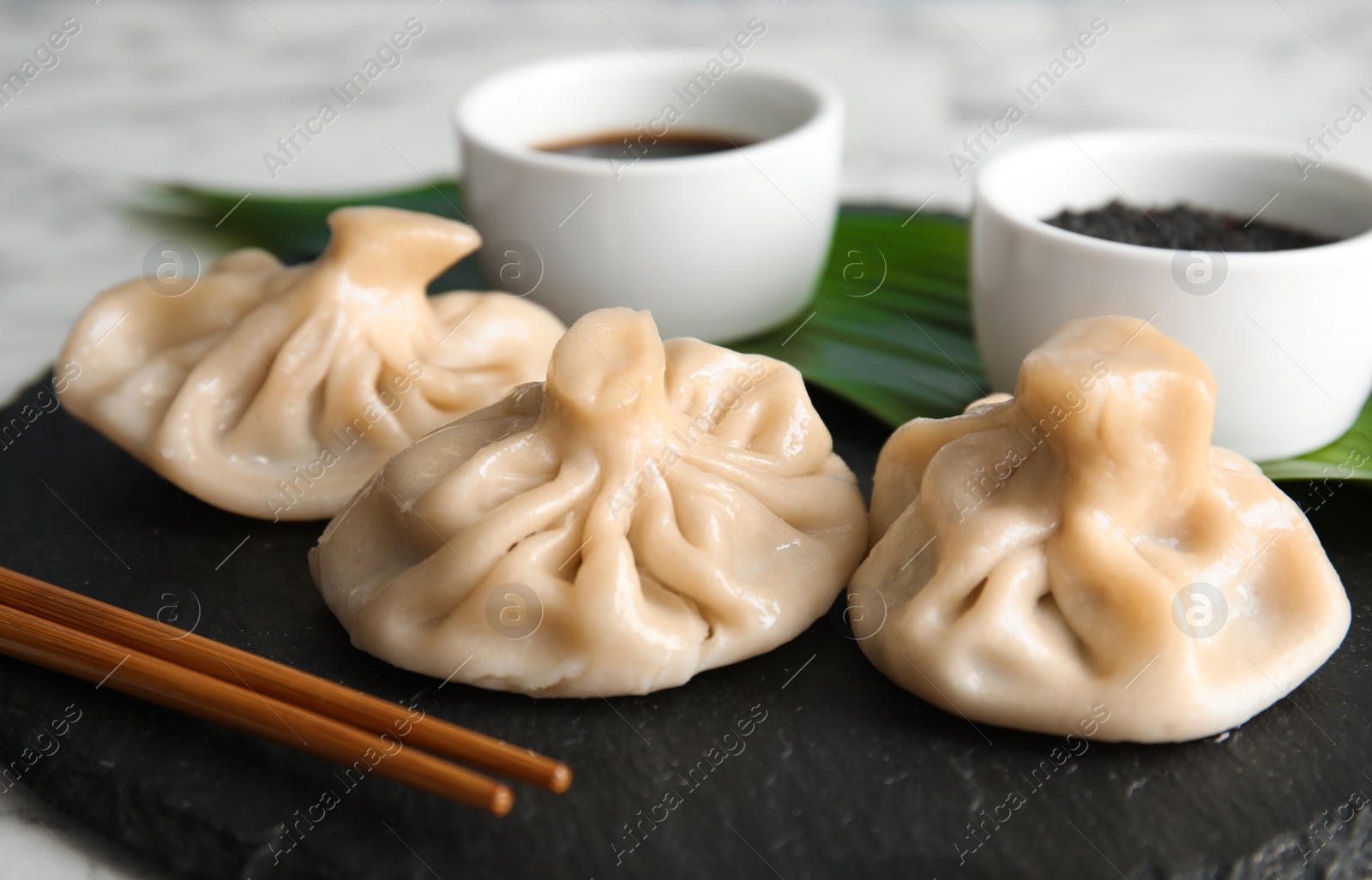 Photo of Slate plate with tasty baozi dumplings on table, closeup