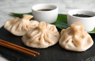 Photo of Slate plate with tasty baozi dumplings on table, closeup