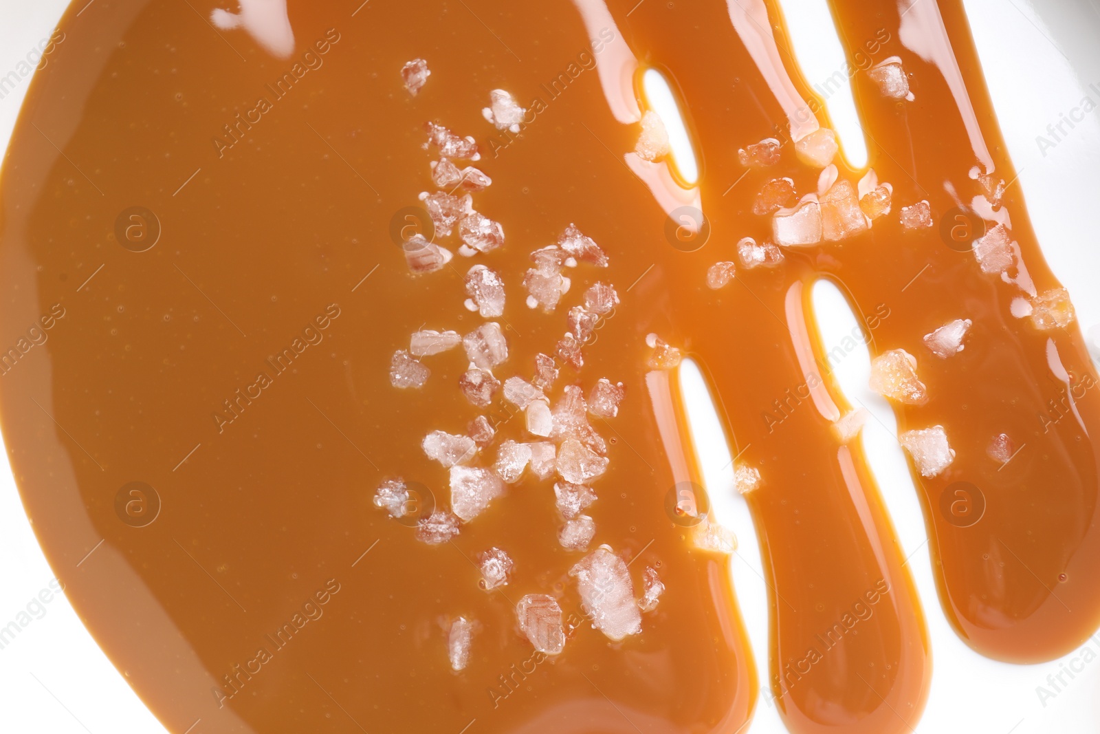 Photo of Delicious caramel sauce with sea salt on white background, top view