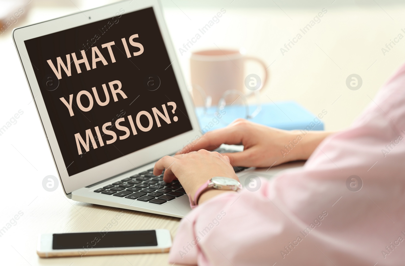 Image of Young woman using modern laptop with question WHAT IS YOUR MISSION? on screen indoors, closeup