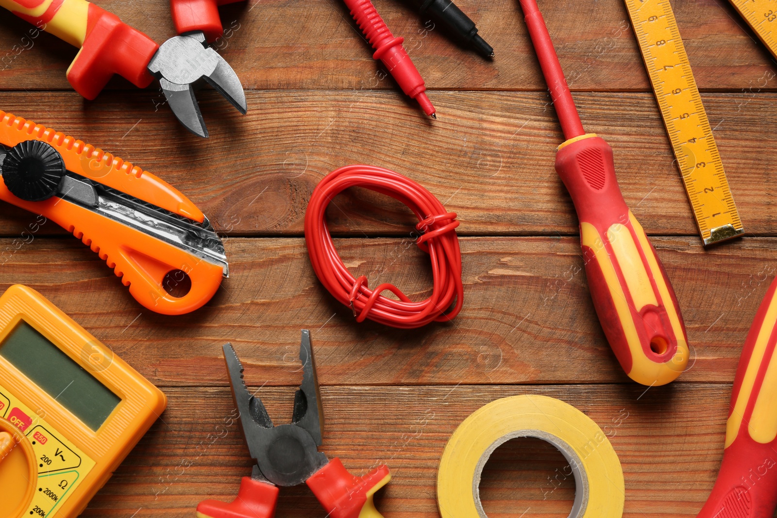 Photo of Wire and electrician's tools on wooden table, flat lay