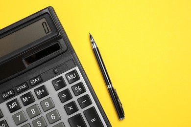 Calculator and pen on yellow background, flat lay. Space for text