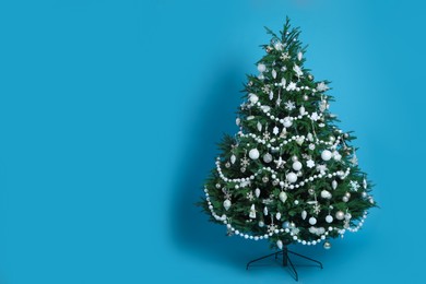 Photo of Beautifully decorated Christmas tree on light blue background