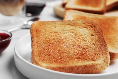 Slices of tasty toasted bread on white table, closeup