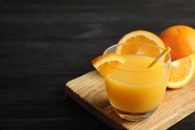 Photo of Glass with orange juice and fresh fruit on wooden background, space for text