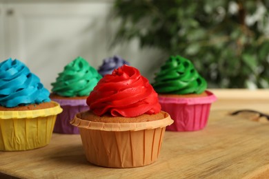 Photo of Delicious cupcakes with cream on wooden table, closeup