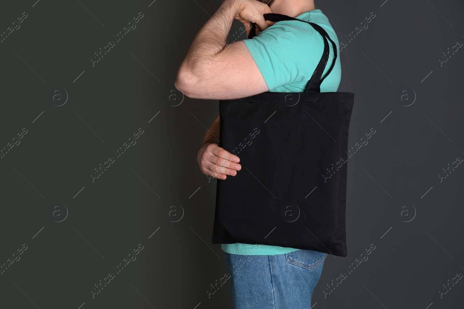 Photo of Man with cotton shopping eco bag on grey background. Mockup for design