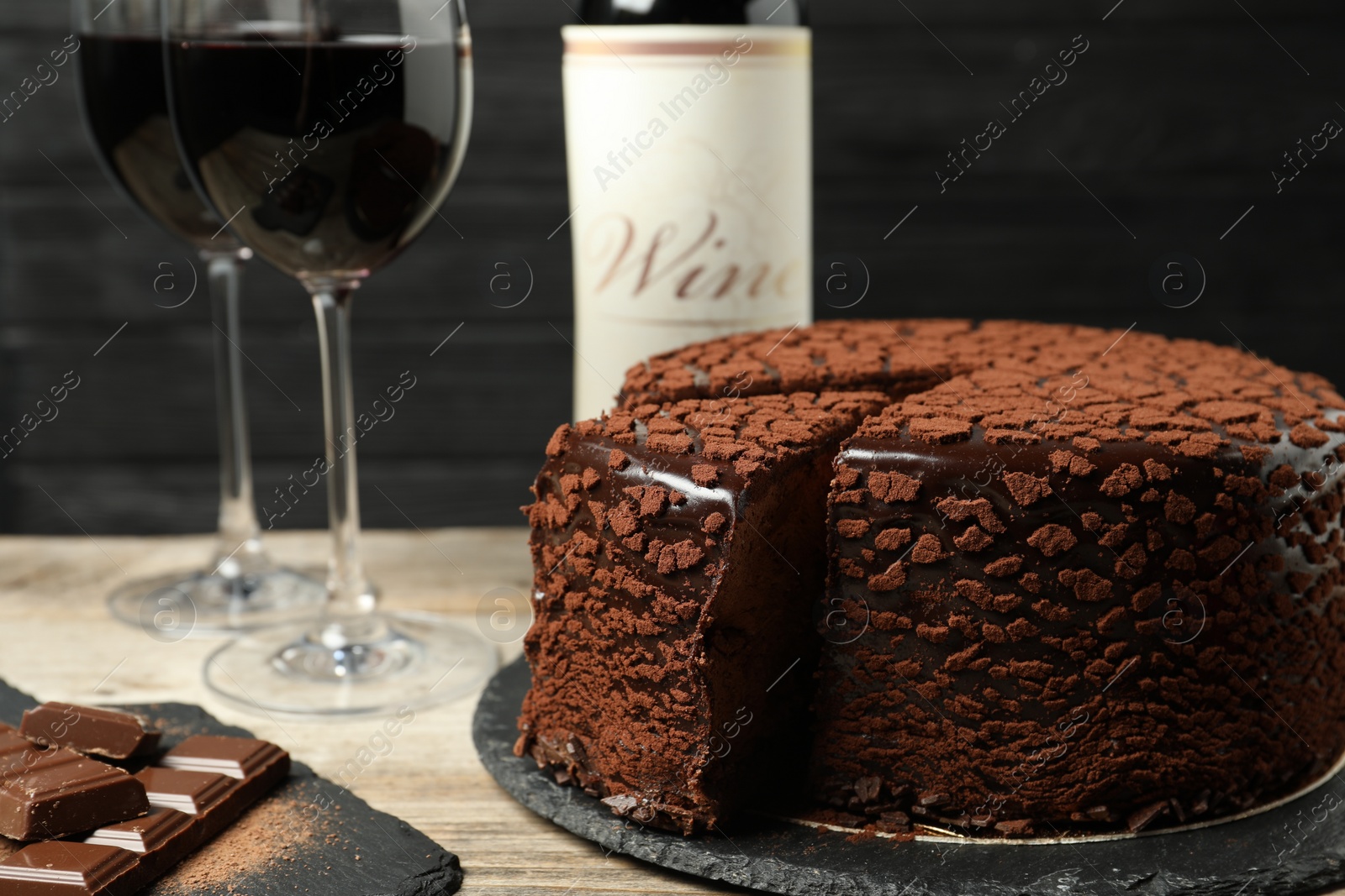 Photo of Delicious chocolate truffle cake and red wine on wooden table