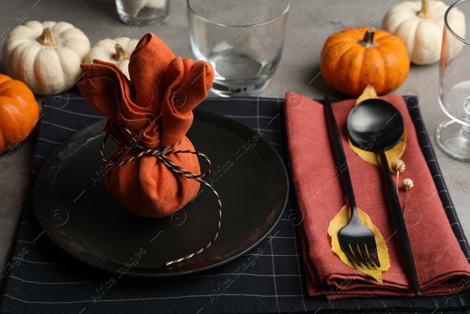 Photo of Seasonal table setting with pumpkins and autumn leaves on grey background, closeup