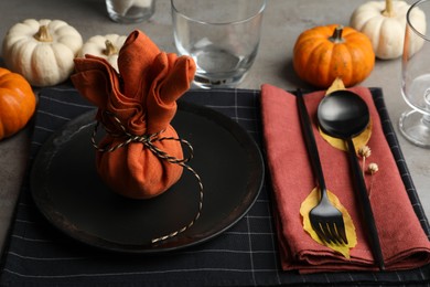 Photo of Seasonal table setting with pumpkins and autumn leaves on grey background, closeup