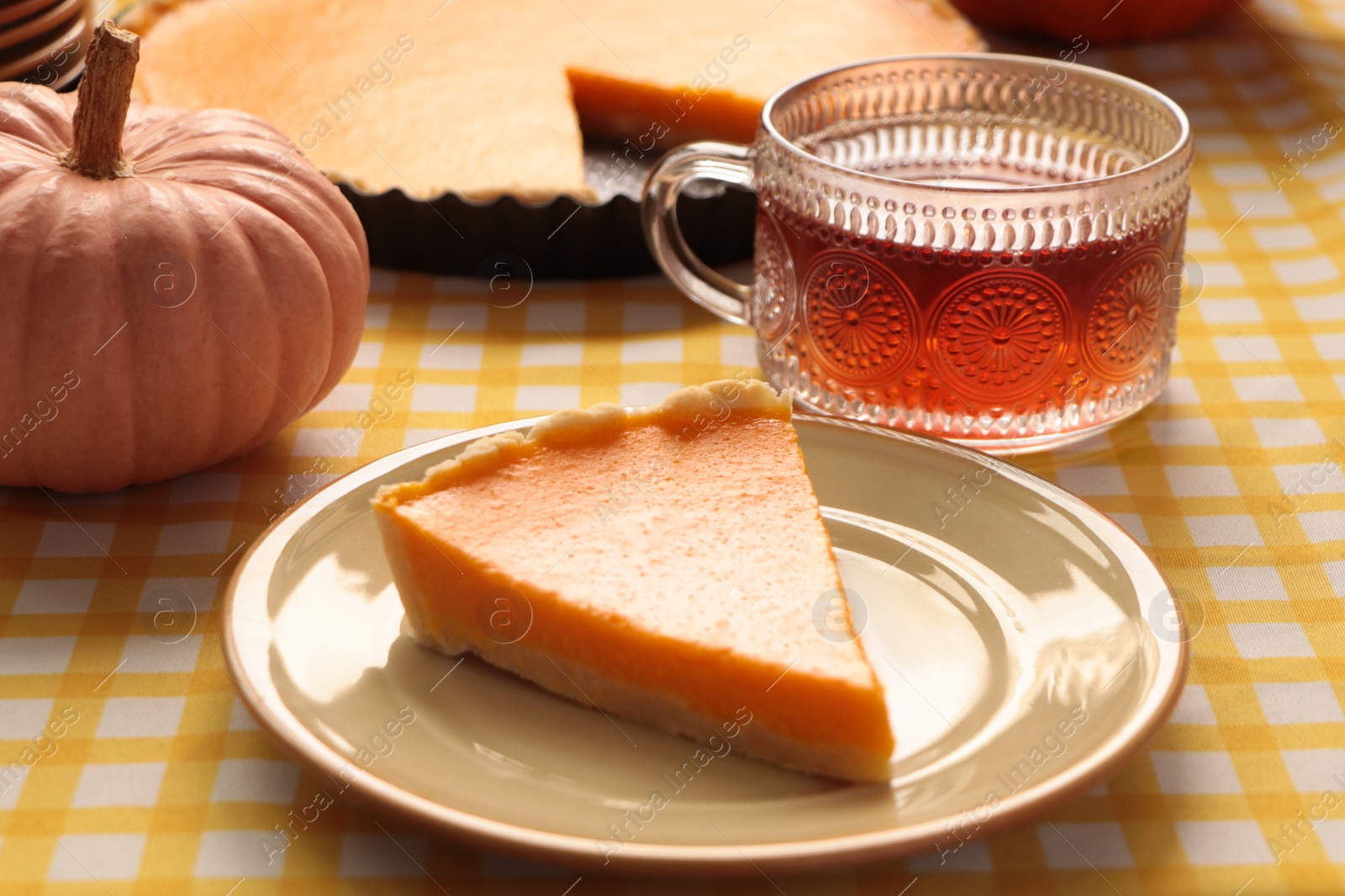 Photo of Piece of fresh homemade pumpkin pie served with tea on table