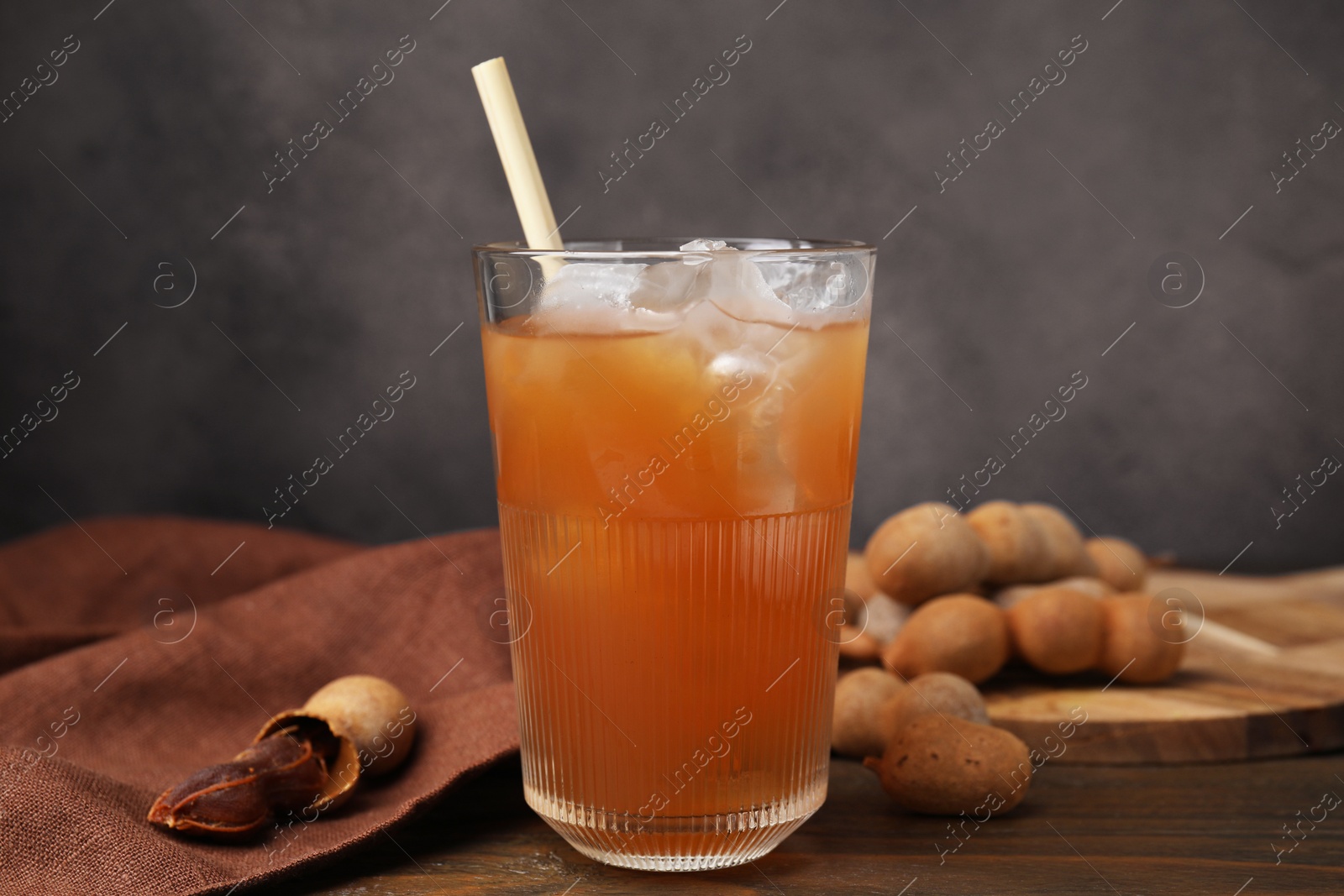 Photo of Freshly made tamarind juice and fresh fruits on wooden table, closeup